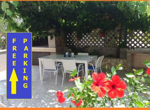un tavolo con sedie e fiori rossi su un patio di Apartments Iris a Korčula