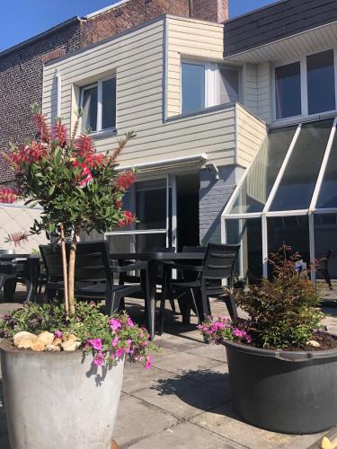 a patio with a table and chairs and flowers at Vakantiewoning De Kassei Geraardsbergen max 12personen in Geraardsbergen