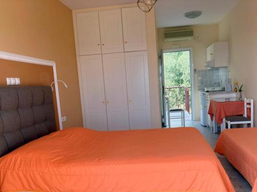 a bedroom with an orange bed and a kitchen at Diona Studios in Lourdhata
