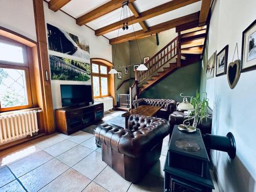 Křimov的住宿－Hunter's lodge Oliver，客厅配有皮革家具和楼梯