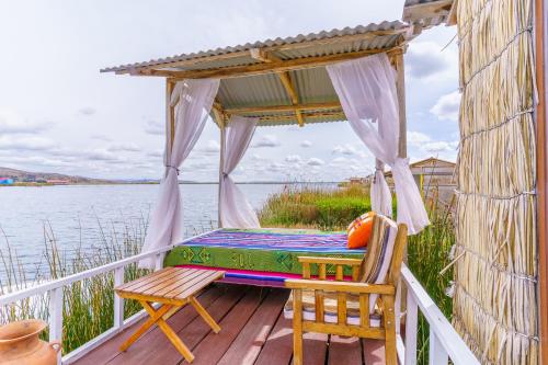 a porch with a bed and two chairs on a deck at Titicaca tikary's lodge in Puno