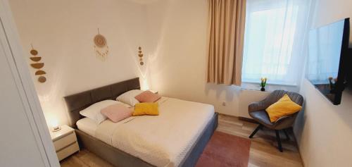 a small bedroom with a bed and a chair at AJP Nova3 Lux Apartament in Szczecin