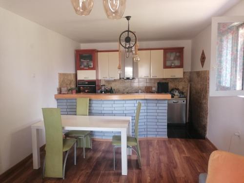 eine Küche mit einem weißen Tisch und grünen Stühlen in der Unterkunft Apartment Uphill Vukovic in Bar