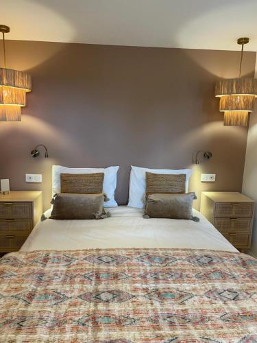 a bedroom with a large bed with two pillows at Villa La Carpenée in Roquefort-les-Pins