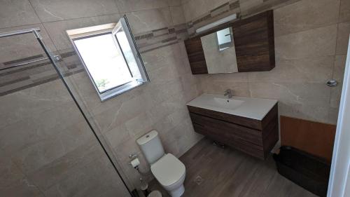 a bathroom with a toilet and a sink and a window at Rapunzel's Tower Mani in Neokhórion