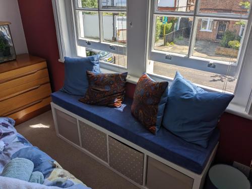 einen Fensterplatz in einem Schlafzimmer mit blauen Kissen in der Unterkunft Comfortable stylish room in Hanwell in Greenford