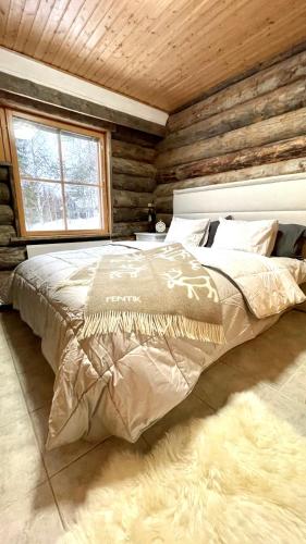 a bed in a room with a wooden wall at Nilimukka log cabin near Levi center in Levi
