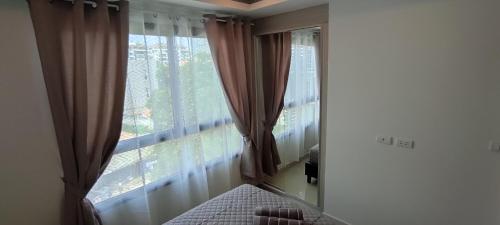 a bedroom with a window with curtains and a bed at Arcadia beach resort in Pattaya South