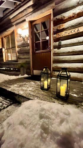 two lights in front of a log cabin with snow at Nilimukka log cabin near Levi center in Levi