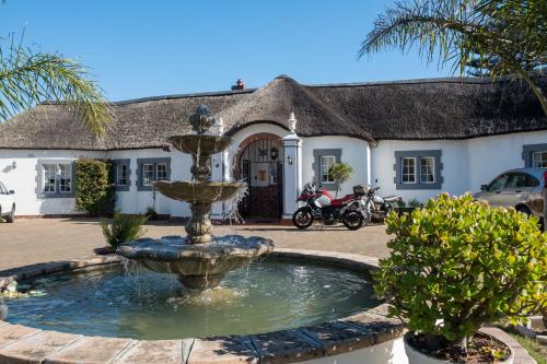 una fontana di fronte a una casa con un edificio di The Sanctuary Guest House Estate a Città del Capo