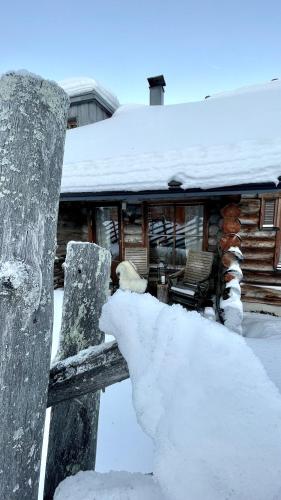 a pile of snow on a fence in front of a house at Nilimukka log cabin near Levi center in Levi