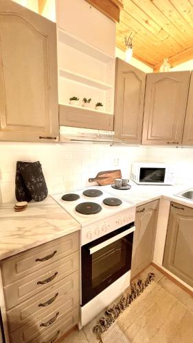 a kitchen with white cabinets and a stove top oven at Nilimukka log cabin near Levi center in Levi