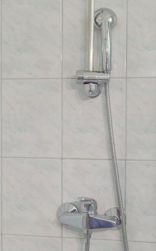 a shower head in a bathroom with white tiles at Walls of Piran Apartments and Rooms in Piran