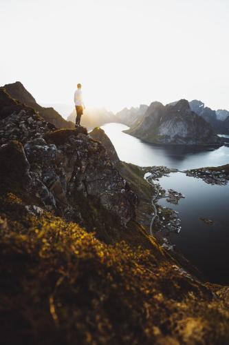 a person standing on top of a mountain overlooking a lake at Solsiden Brygge Rorbuer in Ballstad
