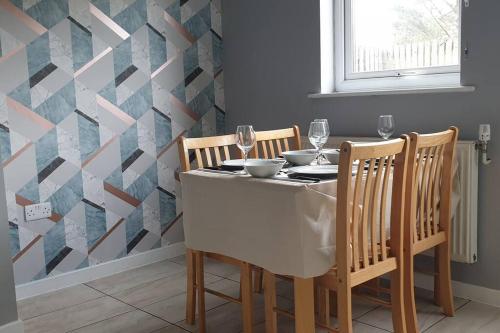 a dining room with a table and chairs and a geometric wall at Ty Fi in Menai Bridge