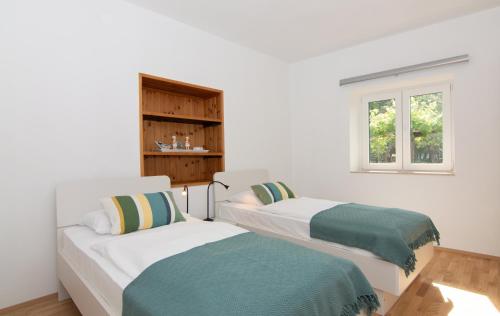 two beds in a white room with a window at Walls of Piran Apartments and Rooms in Piran