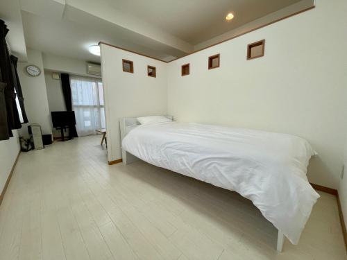 um quarto com uma cama com lençóis brancos em 5-1観光スポット【大通公園】徒歩1分のサービスアパートメントSAPPORO大通西 em Ōdōri