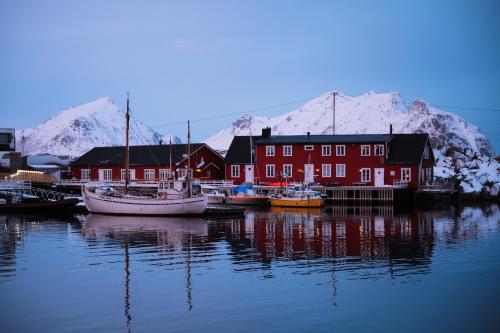 a group of boats docked in a harbor with snow covered mountains at Solsiden Brygge Rorbuer in Ballstad