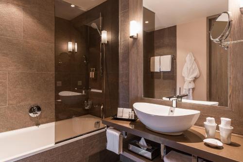 a bathroom with a sink and a bath tub and a sink at AMERON Davos Swiss Mountain Resort in Davos
