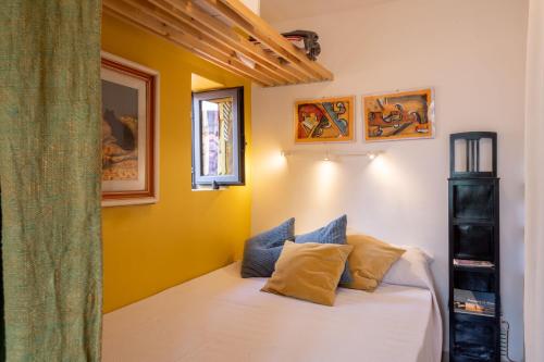 - une chambre avec des murs jaunes et un lit avec des oreillers dans l'établissement Casadellidria, à Catane