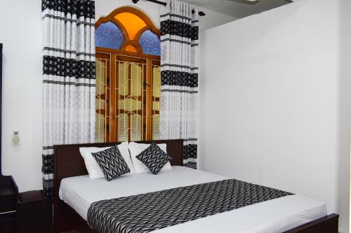 White Moon Beach Resort في ترينكومالي: غرفة نوم مع سرير مع وسائد سوداء وبيضاء