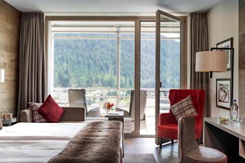 a hotel room with a bed and a large window at AMERON Davos Swiss Mountain Resort in Davos