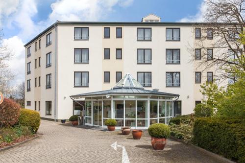 a large white building with a conservatory in front of it at Hotel Strijewski - Apartments in Wolfsburg