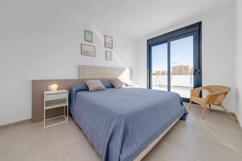 een slaapkamer met een blauw bed en een raam bij Magnífica villa con piscina climatizada in Santiago de la Ribera