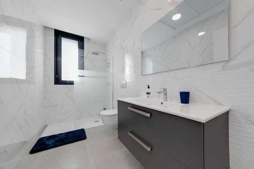 een witte badkamer met een wastafel en een toilet bij Magnífica villa con piscina climatizada in Santiago de la Ribera