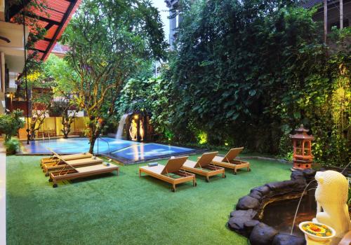 a backyard with lounge chairs and a swimming pool at Green Garden Hotel in Kuta