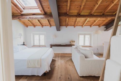 a bedroom with a white bed and two white chairs at Relais Corte Guastalla Apartments in Sona