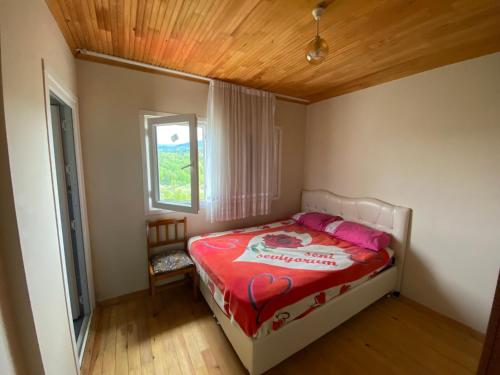 a bedroom with a bed with a red blanket and a window at Hıdırnebimountainhome in Akcaabat