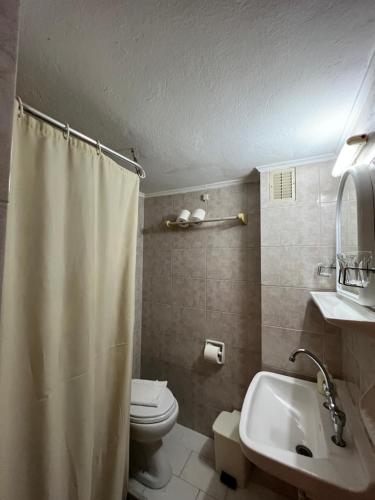 ein Badezimmer mit einem Duschvorhang, einem WC und einem Waschbecken in der Unterkunft Asterias Hotel - Seafront in Parikia