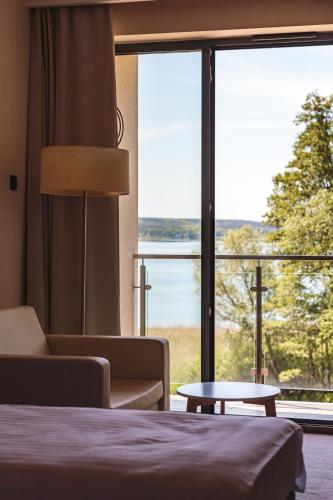 a hotel room with a bed and a large window at Antonińska Resort SPA in Boszkowo