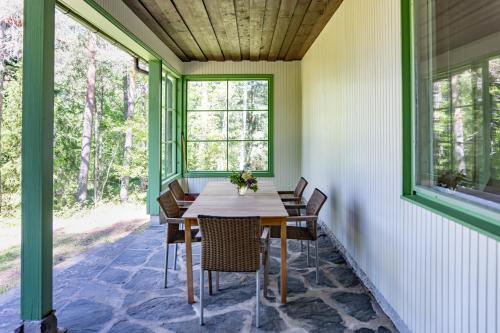 een afgeschermde veranda met een houten tafel en stoelen bij Villa Signell Förby in Särkisalo