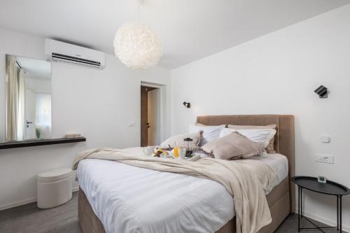 1 dormitorio con 1 cama con sábanas blancas y espejo en Cosy holiday home Infinity with pool and BBQ en Loborika