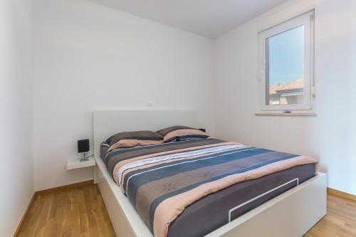 uma cama em um quarto branco com uma janela em Apartment Paradiso with Sea View em Karigador