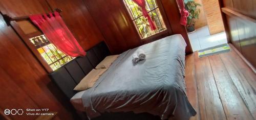 a bed in a small room with two windows at rumah kayu sulawesi antique in Bedugul