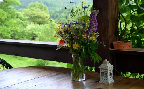 a vase of flowers sitting on a table with a window at Na końcu świata in Dubiecko