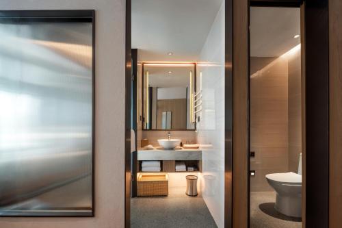 a bathroom with a sink and a toilet and a mirror at Jingju Hotel Shenzhen in Shenzhen