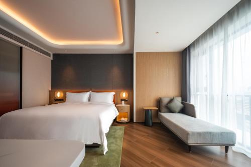 a bedroom with a large white bed and a window at Jingju Hotel Shenzhen in Shenzhen