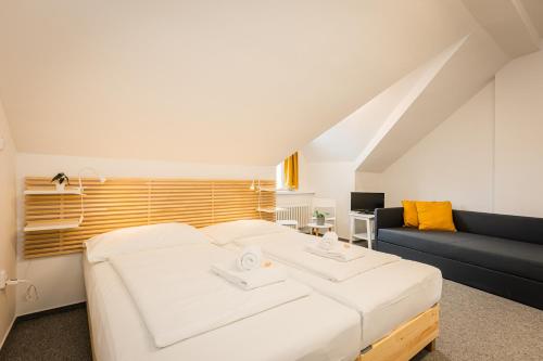 a bedroom with a large white bed and a couch at Self-service Hotel Ostaš Praha in Prague