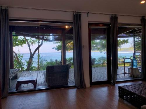 a living room with sliding glass doors with a view of the ocean at Castaway Surf Retreat in Sekongkang