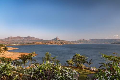 a large body of water with mountains in the background at SaffronStays Shambhala Lakeside-Infinity Pool Villa in Pawna in Malavli