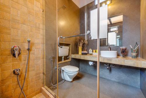 a bathroom with a shower and a toilet and a sink at SaffronStays Shambhala Lakeside-Infinity Pool Villa in Pawna in Malavli