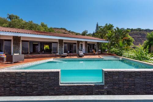 a swimming pool in front of a house at SaffronStays Shambhala Lakeside-Infinity Pool Villa in Pawna in Malavli