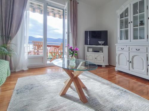 un soggiorno con tavolo in vetro e TV di Apartments Klara a Viganj