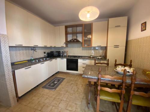 una cocina con armarios blancos y una mesa con sillas. en House Cooper - 2 Min Dal Mare, en Marina di Carrara
