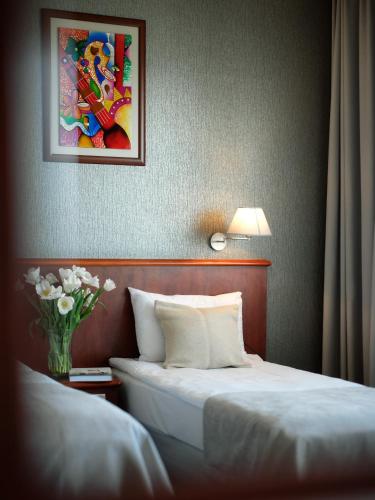 a hotel room with a bed and a vase of flowers at Arka Medical Spa in Kołobrzeg