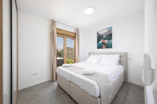 a white bedroom with a large bed and a window at Salt&Soul Residence in Povljana
